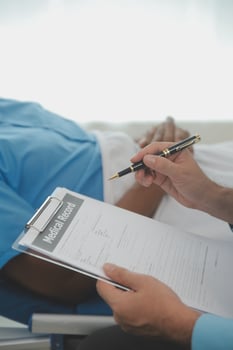 Close up of doctor sitting on bedside of male patient in hospital photo