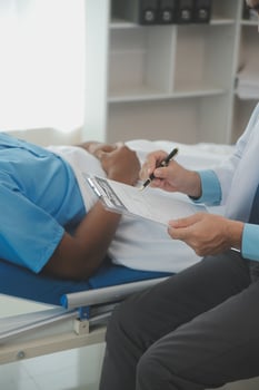 Close up of doctor sitting on bedside of male patient in hospital photo