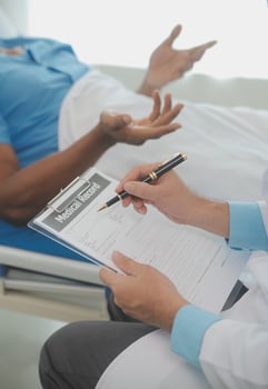 Close up of doctor sitting on bedside of male patient in hospital photo