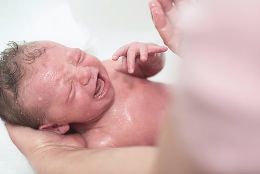 Newborn baby girl taking a first bath photo