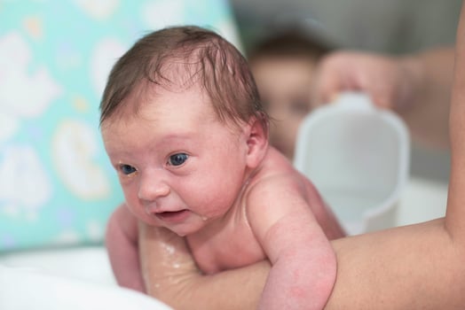 Newborn baby girl taking a first bath photo