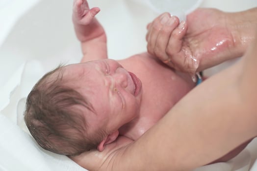 Newborn baby girl taking a first bath photo