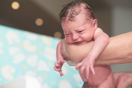 Newborn baby girl taking a first bath photo