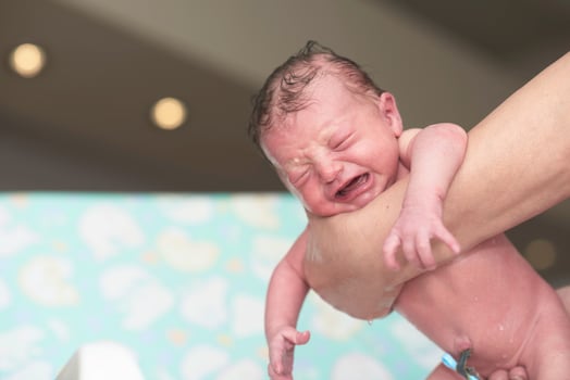 Newborn baby girl taking a first bath photo