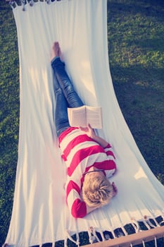 woman reading a book while relaxing on hammock photo