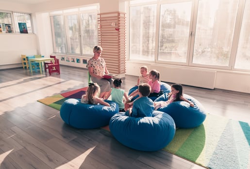 Reading time in elementary school or kindergarten, teacher reading a book to kids in elementary school or kindergaden. Selective focus photo