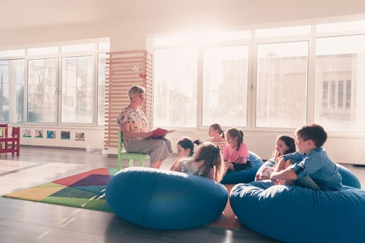 Reading time in elementary school or kindergarten, teacher reading a book to kids in elementary school or kindergaden. Selective focus photo