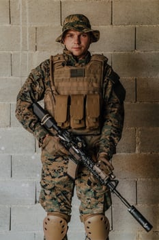 A soldier in uniform stands in front of a stone wall in full war gear preparing for battle photo