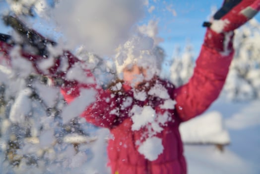 girl throwing fresh snow at beautiful sunny winter day photo
