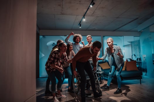 Colleagues help their friend in a wheelchair to take his first steps in a modern office after a serious illness photo
