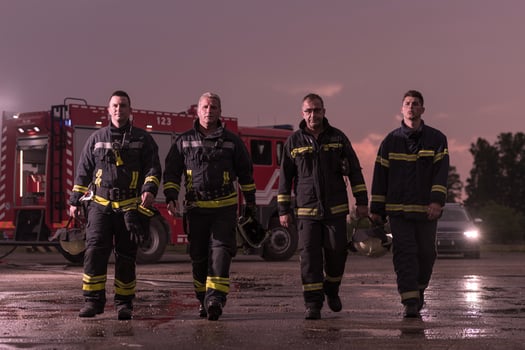 Brave Firefighters Team Walking to the Camera. In Background Paramedics and Firemen Rescue Team Fight Fire in Car Accident, Insurance and Save Peoples Lives concept. photo