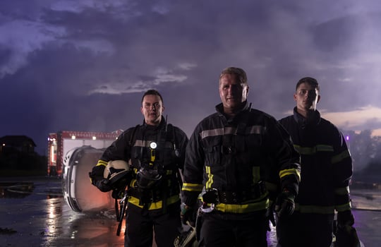 Brave Firefighters Team Walking to the Camera. In Background Paramedics and Firemen Rescue Team Fight Fire in Car Accident, Insurance and Save Peoples Lives concept. photo