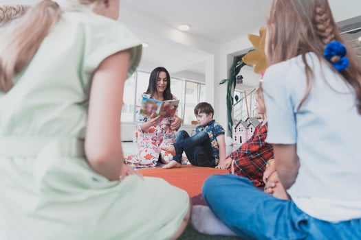 Reading time in an elementary school or kindergarten, a teacher reads a book to children in an elementary school or kindergarten. The concept of pre-school education. Selective focus photo
