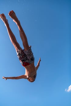 a man in a swimsuit is doing a flip in the air photo