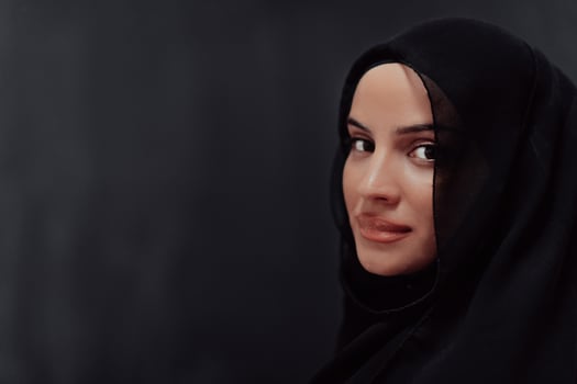 Portrait of beautiful muslim woman in fashionable dress with hijab in front of black chalkboard representing modern islam fashion and ramadan kareem concept photo