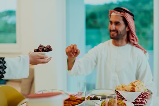 Modern multiethnic muslim family sharing a bowl of dates while enjoying iftar dinner together during a ramadan feast at home photo