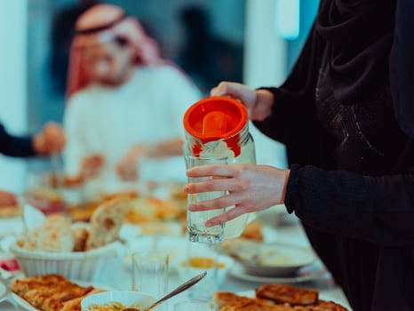 Eid Mubarak Muslim family having Iftar dinner drinking water to break feast. Eating traditional food during Ramadan feasting month at home. The Islamic Halal Eating and Drinking photo