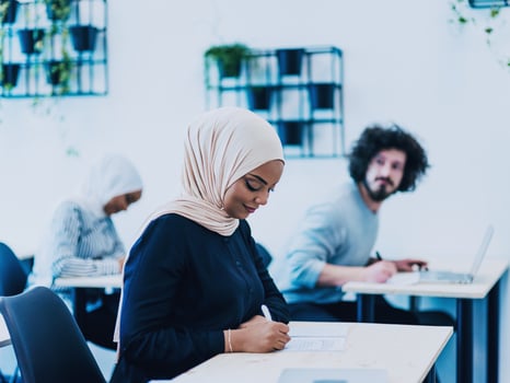 Photo of an African American Muslim woman being educated about business development in a modern classroom