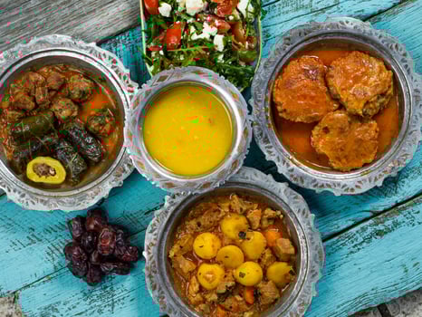 Eid Mubarak Traditional Ramadan Iftar dinner. Assorted tasty food in authentic rustic dishes on wooden blue background. Turkish Bosnian food meat kebab, pita, Sarma, klepe, sogan dolma. photo
