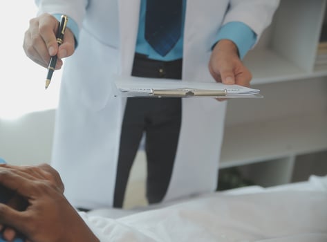 Close up of doctor sitting on bedside of male patient in hospital photo