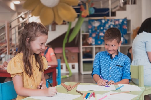 Cute girl and boy sit and draw together in preschool institution photo