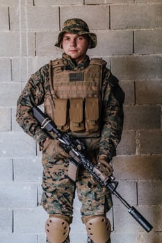 A soldier in uniform stands in front of a stone wall in full war gear preparing for battle photo