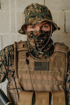 A soldier in uniform stands in front of a stone wall in full war gear preparing for battle photo