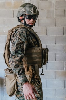 A soldier in uniform stands in front of a stone wall in full war gear preparing for battle photo