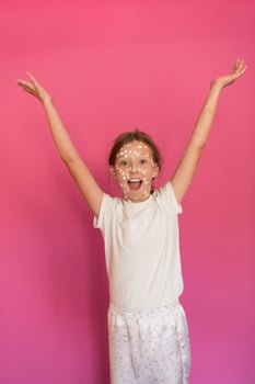 Portrait of a little school girl with chickenpox, antiseptic cream applied to face and body .Colorful background. photo