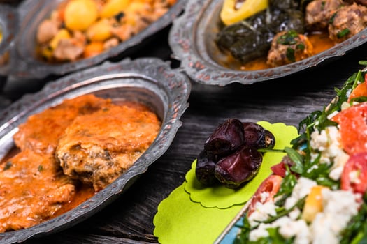Eid Mubarak Traditional Ramadan Iftar dinner. Assorted tasty food in authentic rustic dishes on wooden blue background. Turkish Bosnian food meat kebab, pita, Sarma, klepe, sogan dolma. photo
