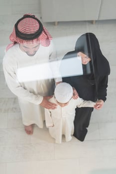 Portrait of a young happy Arabian Muslim family couple with a son in traditional clothes spending time together photo