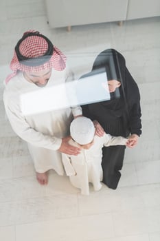 Portrait of a young happy Arabian Muslim family couple with a son in traditional clothes spending time together photo