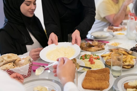 Eid Mubarak Muslim family having Iftar dinner drinking water to break feast. Eating traditional food during Ramadan feasting month at home. The Islamic Halal Eating and Drinking at modern western Isla photo