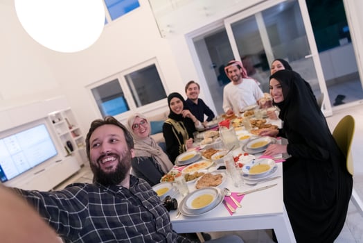Eid Mubarak Muslim family having Iftar dinner taking pictures with mobile phone while eating traditional food during Ramadan feasting month at home. The Islamic Halal Eating and Drinking Islamic famil photo