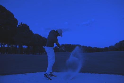 golfer hitting a sand bunker shot on sunset photo
