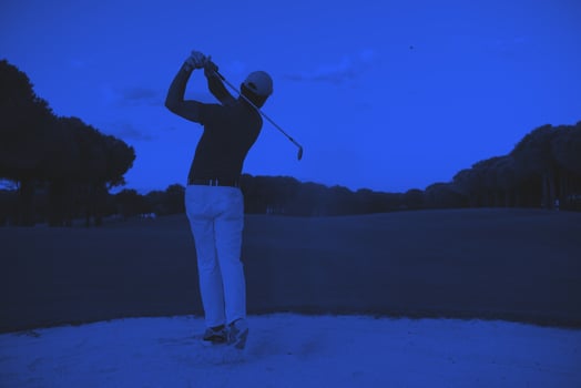golfer hitting a sand bunker shot on sunset photo