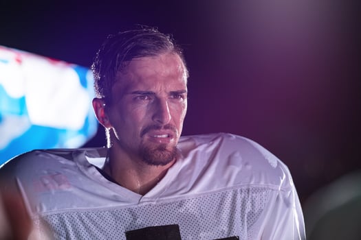 American Football Field Lonely Athlete Warrior Standing on a Field Holds his Helmet and Ready to Play. Player Preparing to Run, Attack and Score Touchdown. Rainy Night with Dramatic Fog, Blue Light photo
