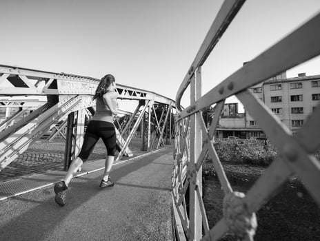 woman jogging across the bridge at sunny morning photo