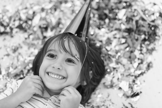 kid blowing confetti while lying on the floor photo
