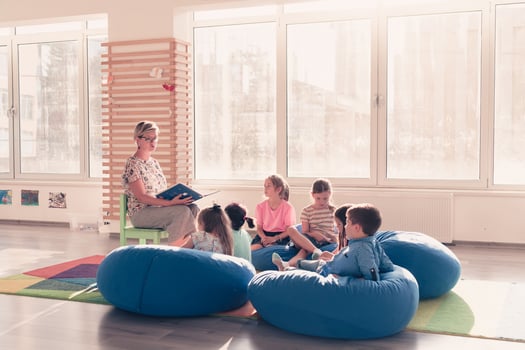 Reading time in elementary school or kindergarten, teacher reading a book to kids in elementary school or kindergaden. Selective focus photo
