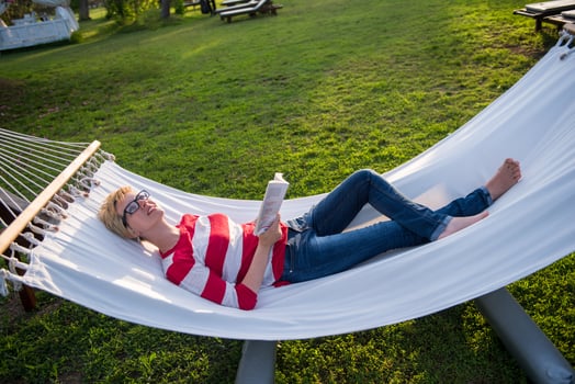 woman reading a book while relaxing on hammock photo