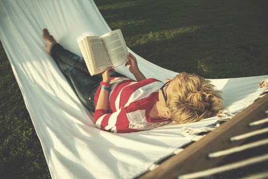 woman reading a book while relaxing on hammock photo