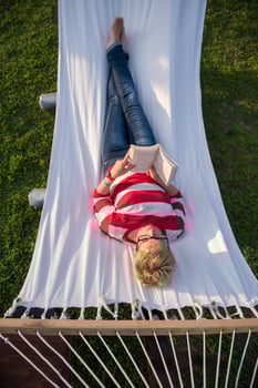 woman reading a book while relaxing on hammock photo