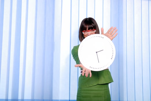 .a pretty business woman hiding behind a clock photo