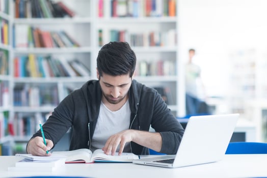 student in school library using laptop for research photo