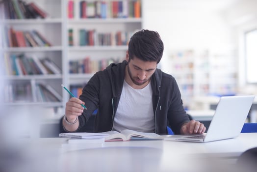 student in school library using laptop for research photo