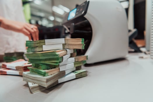 Bank employees using money counting machine while sorting and counting paper banknotes inside bank vault. Large amounts of money in the bank photo