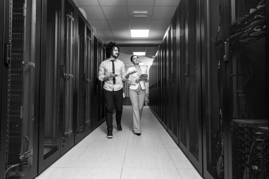 engineer showing working data center server room to female chief photo