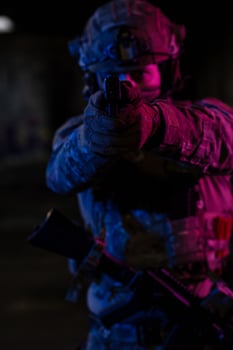 Soldier of army elite forces, special security service fighter with hidden behind mask and glasses face, in helmet and load carriage system, aiming with service pistol low key. photo