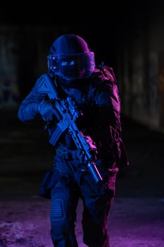 Army soldier in Combat Uniforms with an assault rifle and combat helmet night mission dark background. Blue and purple gel light effect. photo